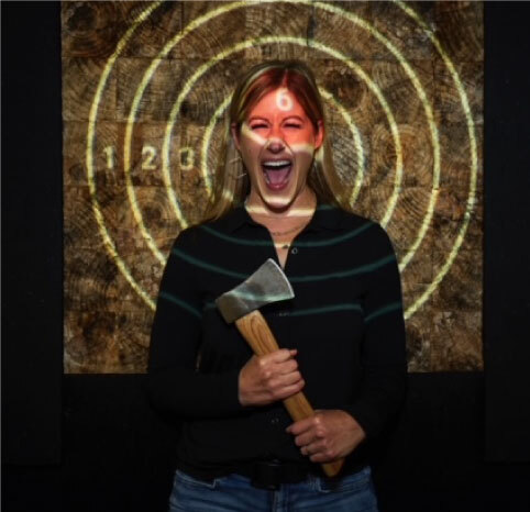 funny axe throwing picture of a girl standing in front of an axe throwing target and screaming